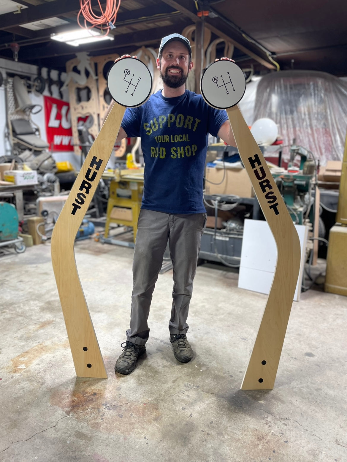Rod Shop Collective founder standing next to a giant five foot handmade wooden Hurst shifter wall art — Hand Built collection — Louisville, Kentucky