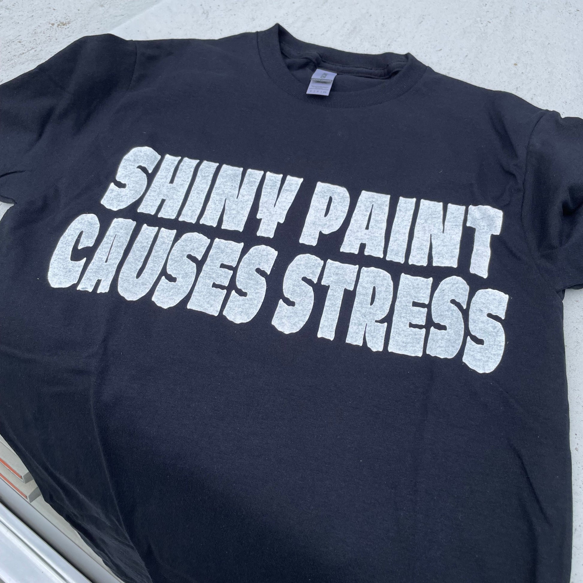 Shiny Paint Causes Stress t-shirt laid on the hood of a Chevy C10 truck — the original patina hot rod tee — Rod Shop Collective — Louisville, Kentucky