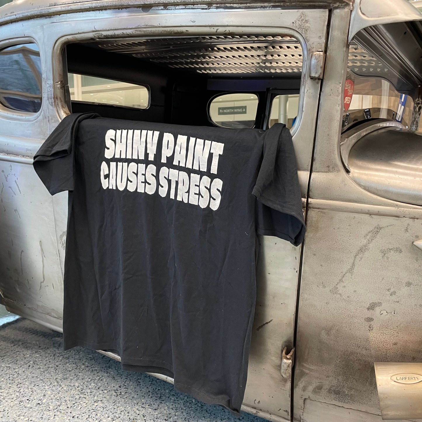 Shiny Paint Causes Stress t-shirt laid on the bare metal 1930 Model A coupe — the original patina hot rod tee — Rod Shop Collective — Louisville, Kentucky